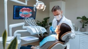 Odontólogo trabajando en una paciente para aplicar carillas dentales, asegurando que las carillas dentales duren toda la vida.